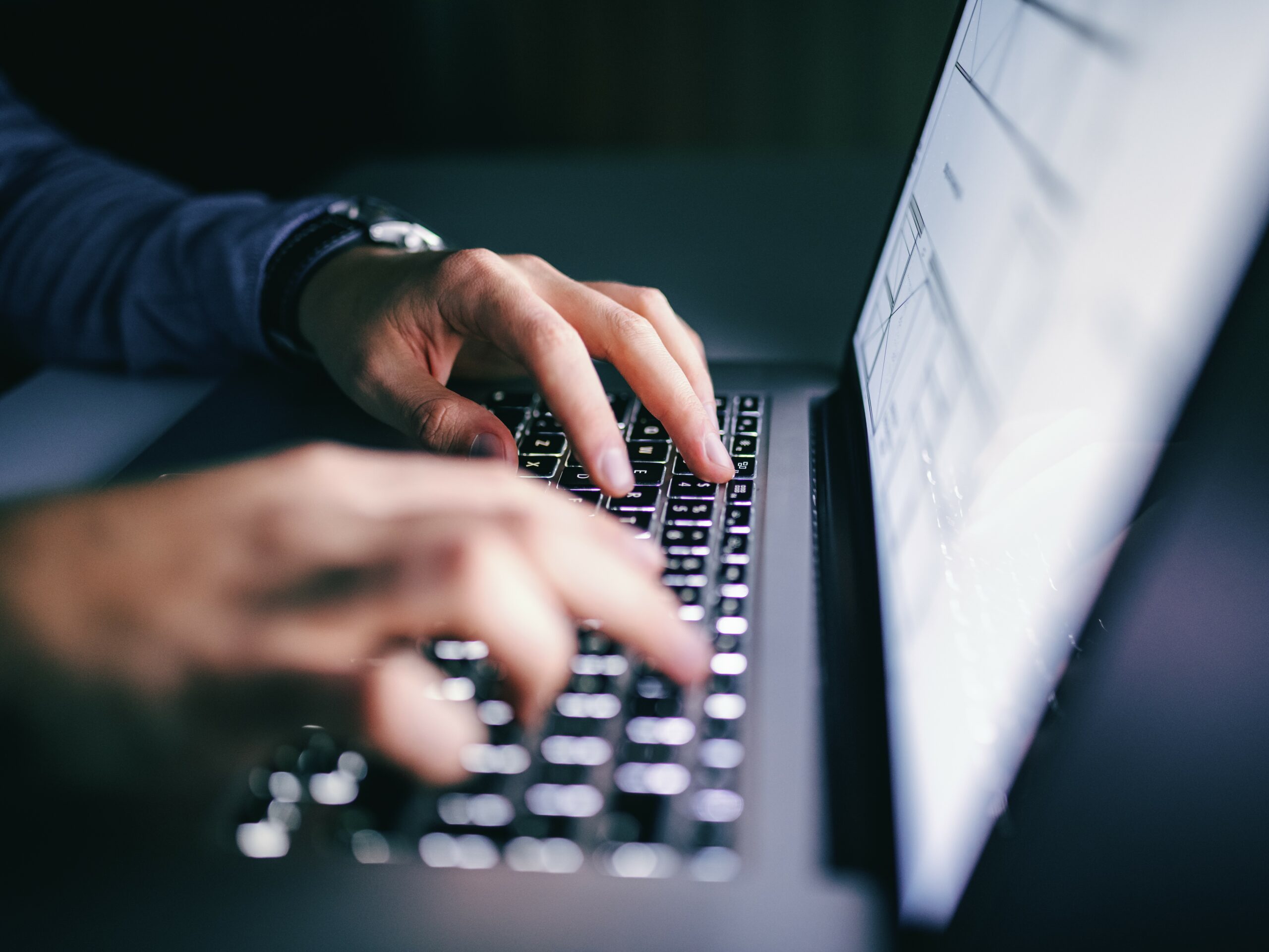 Close up of hands typing on laptop. Night work concept.